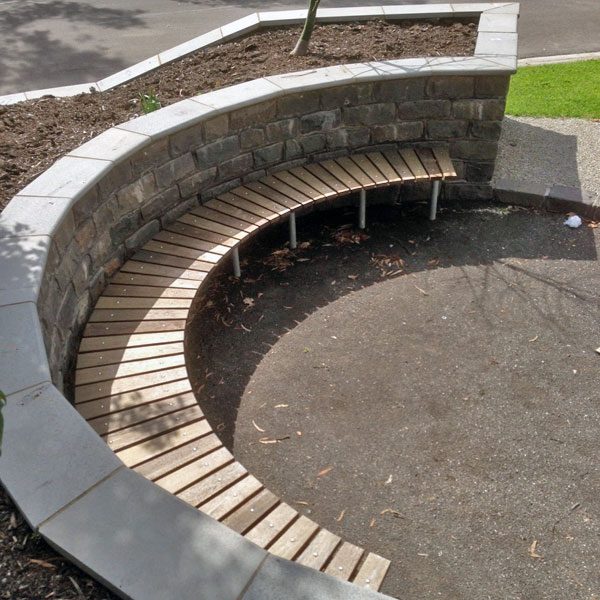 Public curved park bench built into retaining wall