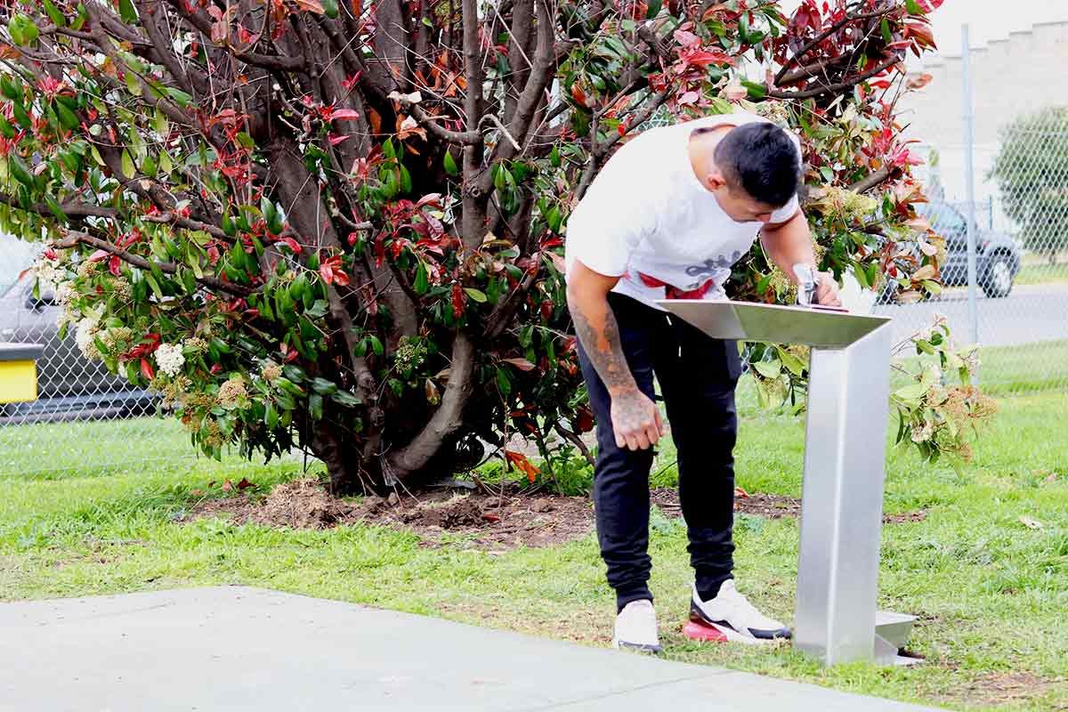 Kiama drinking fountain bike Person using a stainless steel outdoor drinking fountain in a public park setting.