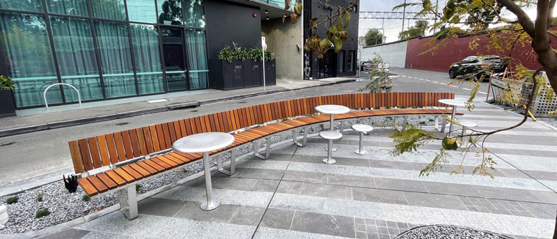Custom sweeping park seat with round cafe tables