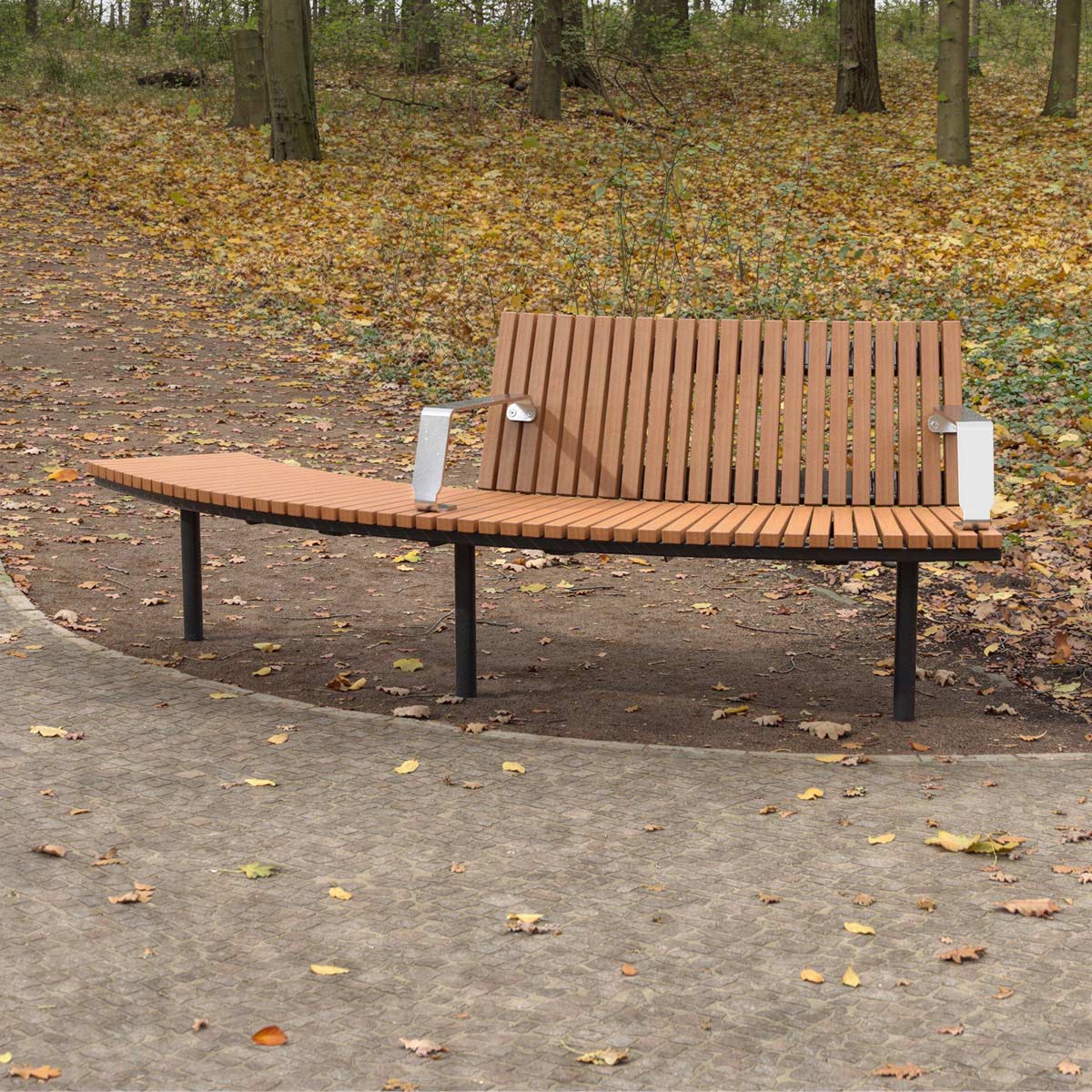 DDA-compliant curved wooden park bench with backrest on half of the bench and metal armrests next to a footpath in a park.