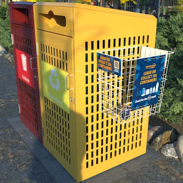 Red and yellow recycling bins in a park, with labelled sections for rubbish and recyclables. A wire basket for CDS containers attached to the recyclable bin.