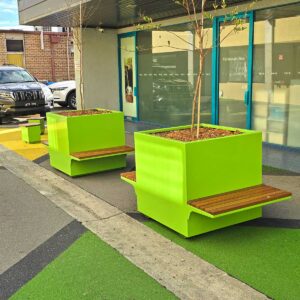 Bright coloured street planters with in integrated seating placed in an alleyway