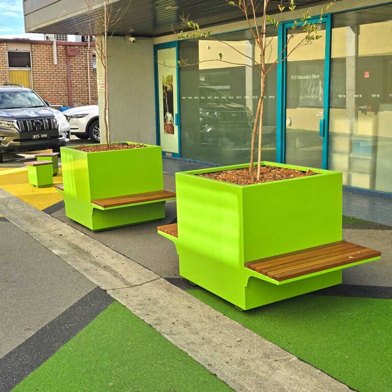 Bright coloured street planters with in integrated seating placed in an alleyway